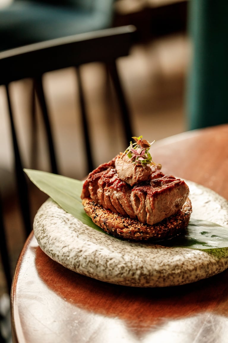 Elegant plated dessert with chocolate mousse on a cookie base, garnished with edible flower and microgreens, served on a stone plate